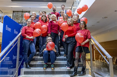 Pracownicy Politechniki Rzeszowskiej w czerwonych strojach, z czerwonymi balonami, 