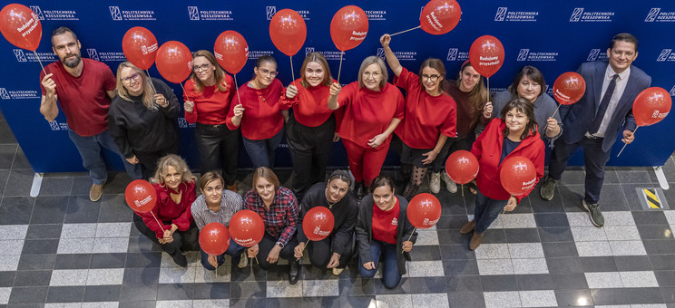Pracownicy Politechniki Rzeszowskiej w czerwonych strojach, z czerwonymi balonami, 