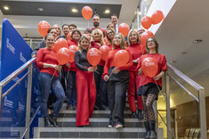 Pracownicy Politechniki Rzeszowskiej w czerwonych strojach, z czerwonymi balonami, 